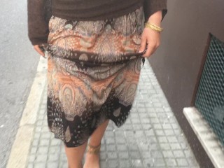 young female hippie is walking barefoot in public street